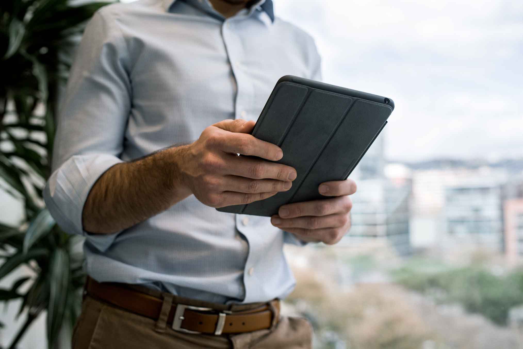 Detail of a man holding a tablet in his hands.