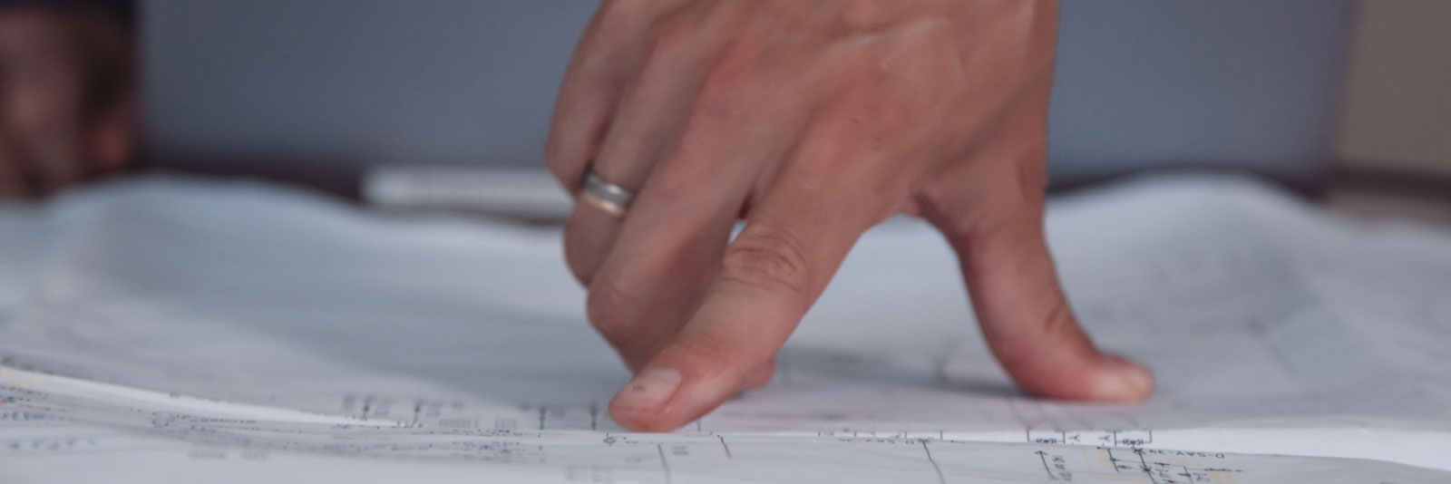 The picture shows a hand pointing to drawing of a plant documentation from Menger Group.